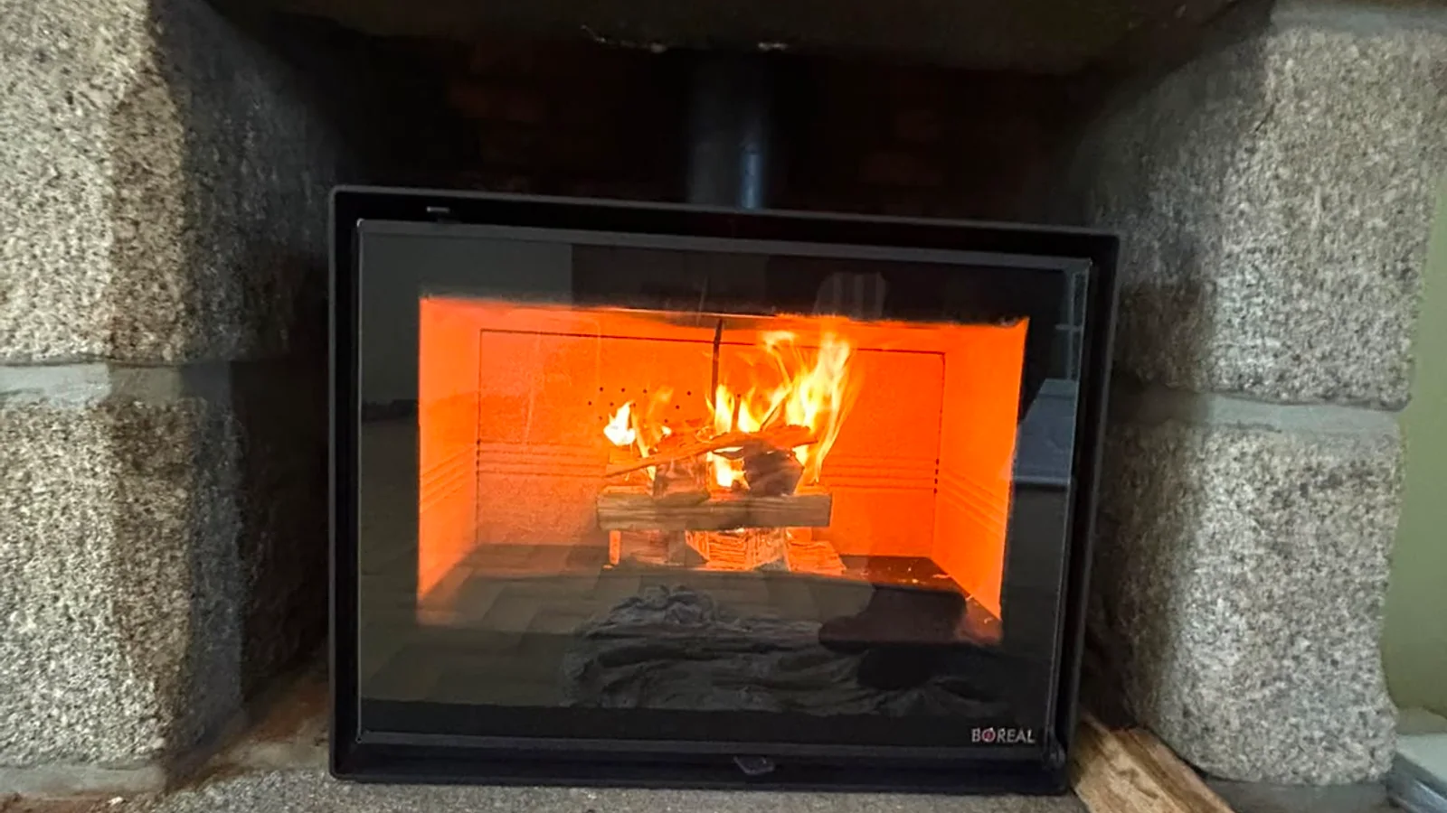 Flambée dans un insert bois encastré sous un linteau en pierre de taille · Touflamme Ramonage Finistère Nord